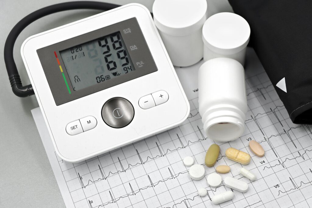 pexels-photo-32210639-32210639 Blood pressure monitor with pills on ECG sheet, essential for heart health management.